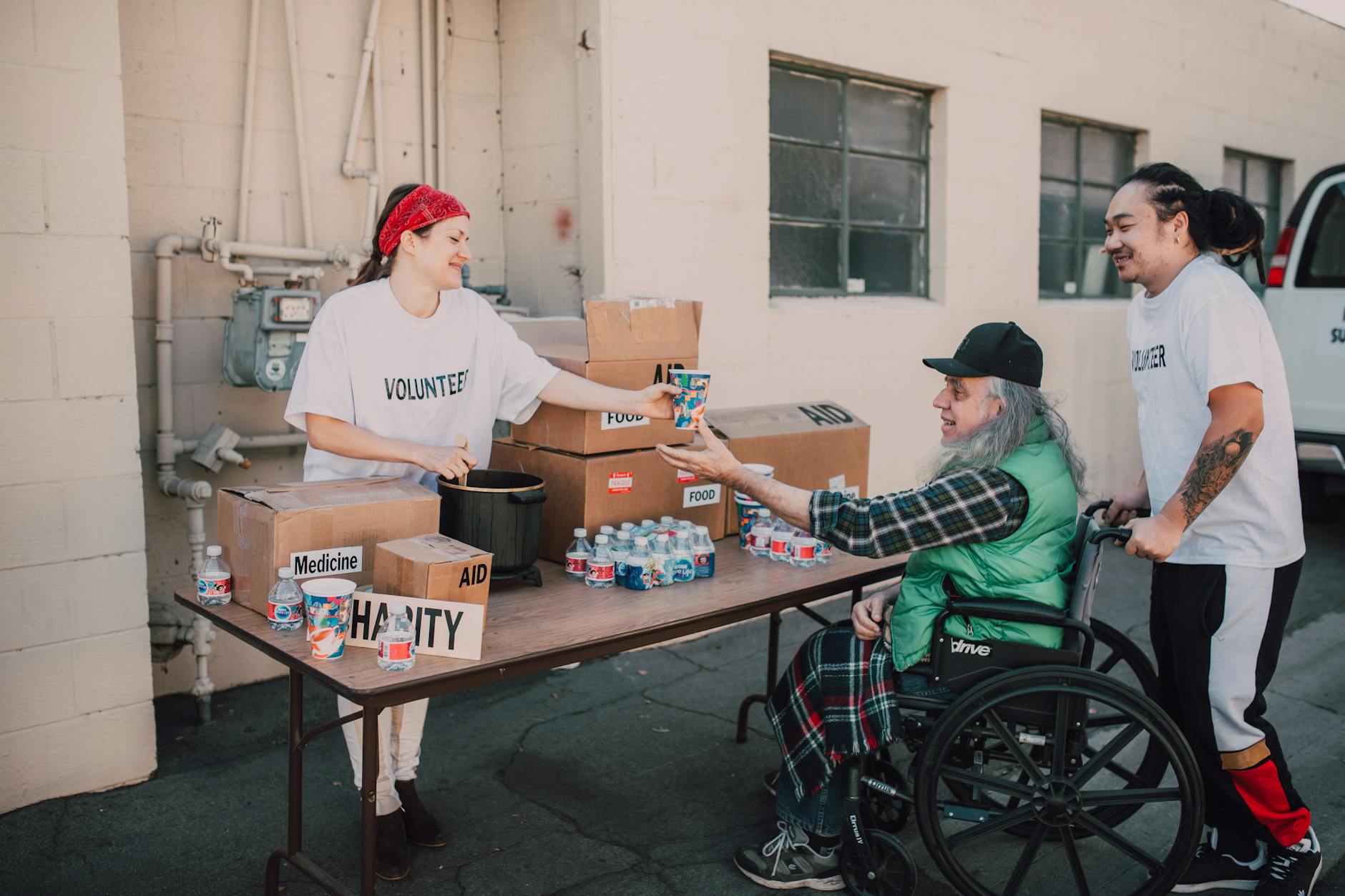 an elderly mab receiving a cup of drink from a volunteer