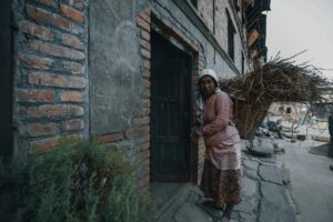 black woman carrying twigs in basket on urban street