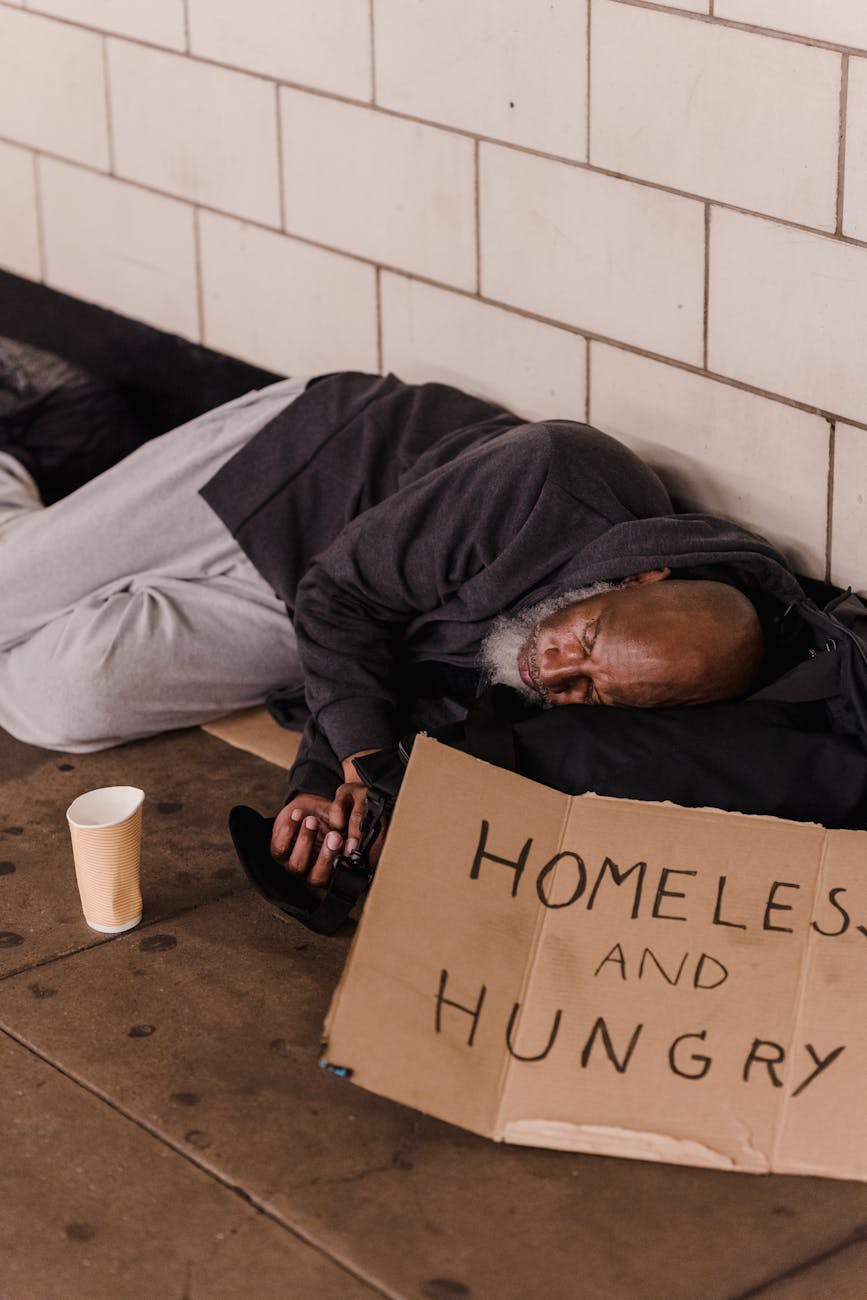 an elderly man sleeping on the floor beside a wall