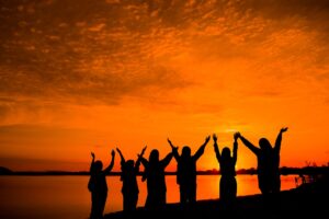 group of friends on lakeshore at sunset