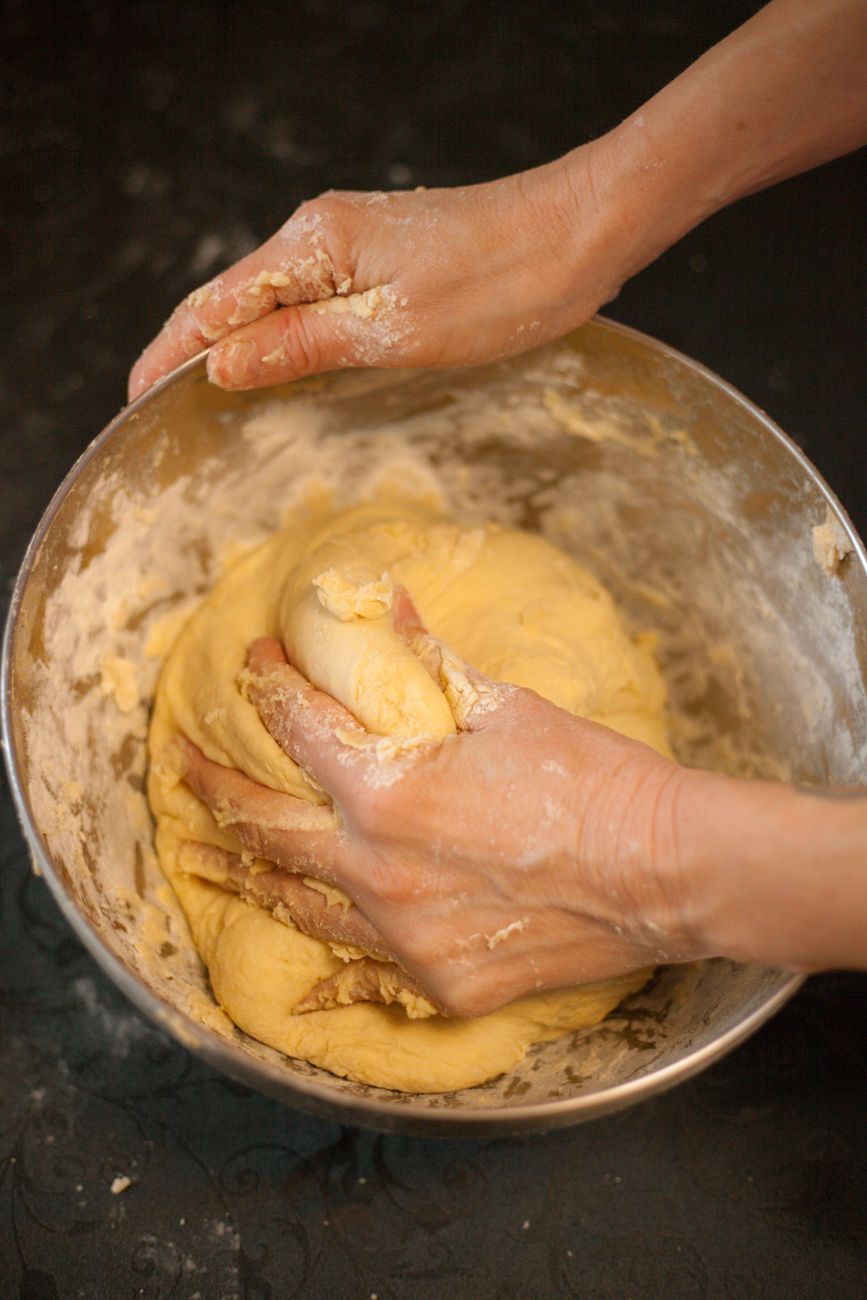 hands kneading dough in metal bowl